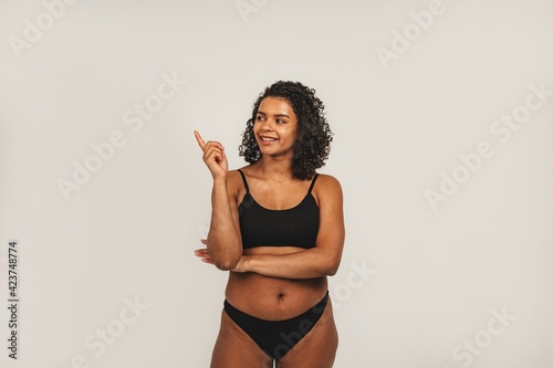 Photo of attractive black woman wears black underwear, wondering about. Isolated over white background. Natural beauty and health © Ivan