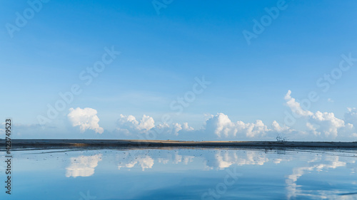 blue sky and white clouds over sand beach reflection on the sea 