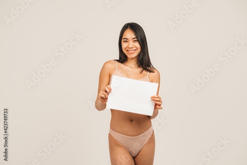 Photo of natural woman face, wears underwear and holds white plate . Isolated over white background. Natural beauty and health. Clean skin and cute smile