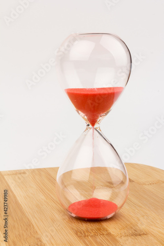 Crystal hourglass on wooden background as a concept of passing time for business term, urgency and outcome of time.