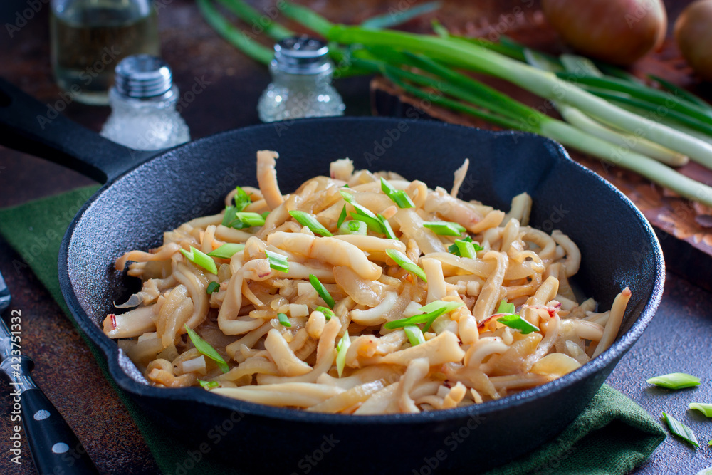 fried calamari in soy sauce with green onions in a cast iron pan, selective focus fried calamari in soy sauce with green onions in a cast iron pan, selective focus