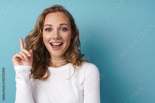 Blonde happy woman pointing finger upward and smiling