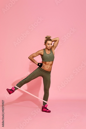 woman in sportswear exercising with rubber resistance band