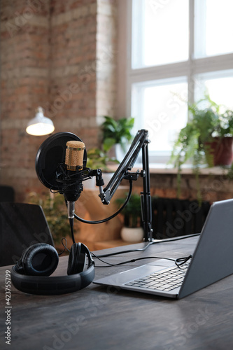 Image of table with laptop microphone and headphones preparing for recording in studio