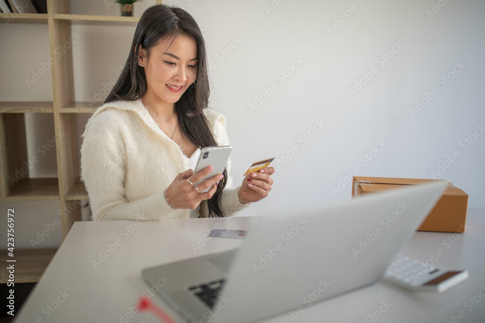 Portrait of young woman using credit card and  laptop for Online shopping	at home office