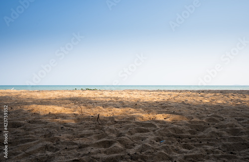 Bright blue sky and sand at the beach, warm sunlight.