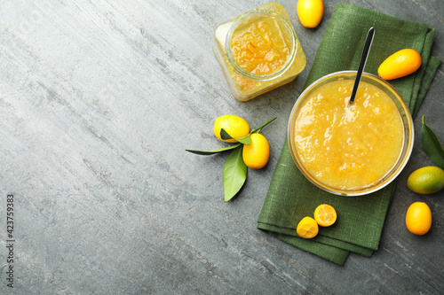 Fototapeta Naklejka Na Ścianę i Meble -  Delicious kumquat jam in bowl and fresh fruits on grey table, flat lay. Space for text