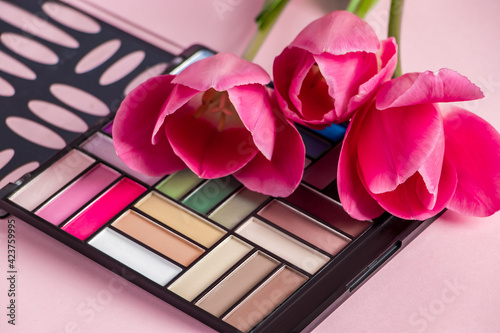 Set of cosmetics and flowers on a pink background. Makeup and beauty products.