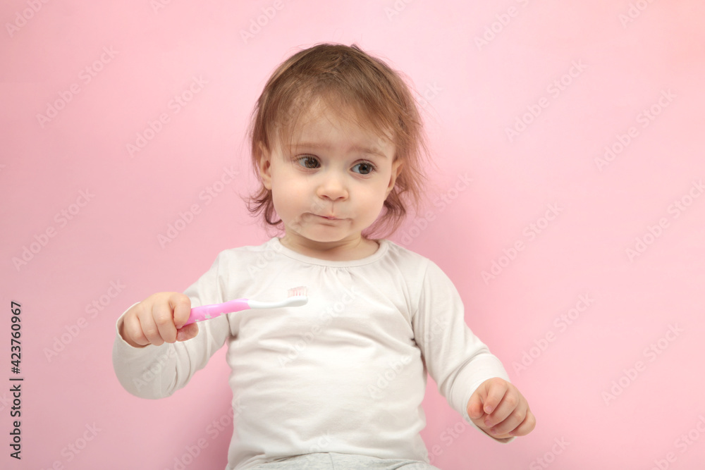 Cute baby girl brushing teeth on pink background. Cute baby girl brushing teeth on pink background.