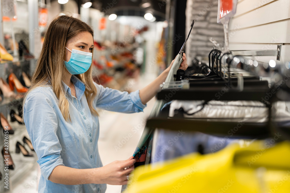 Woman shopping for clothes wearing mask and social distancing