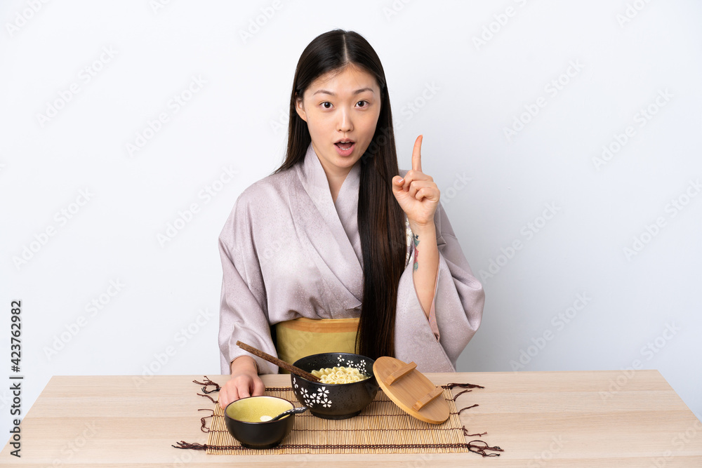 Young Chinese girl wearing kimono and eating noodles thinking an idea ...
