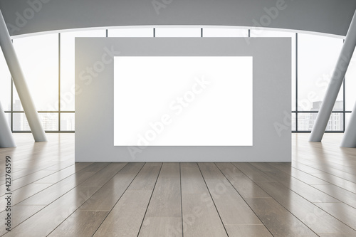 Stampa su tela Blank white poster on grey partition in sunny spacious hall with wooden floor and city view