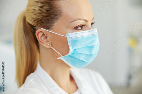 Closeup of beautiful lab assistant with protective sterile face mask on. Covid 19 outbreak concept.