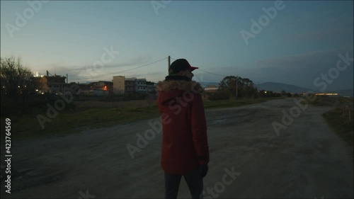 Ragazzo cammina dopo il tramonto in una strada sterrata photo