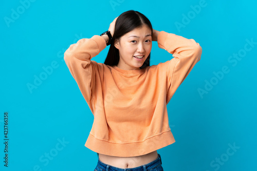 Young Chinese girl over isolated blue background laughing