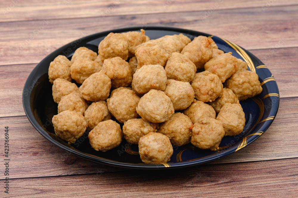 Meat or Fried Shrimp Balls placed in a black plate and place on wooden table. Meat or Fried Shrimp Balls placed in a black plate and place on wooden table.