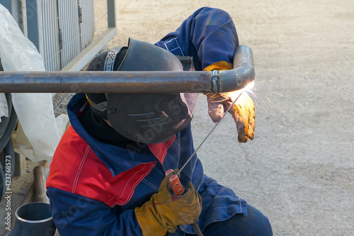 Working. A welder welds a pipe. Manual arc welding of technological pipelines DN50 for an oil refinery in Russia