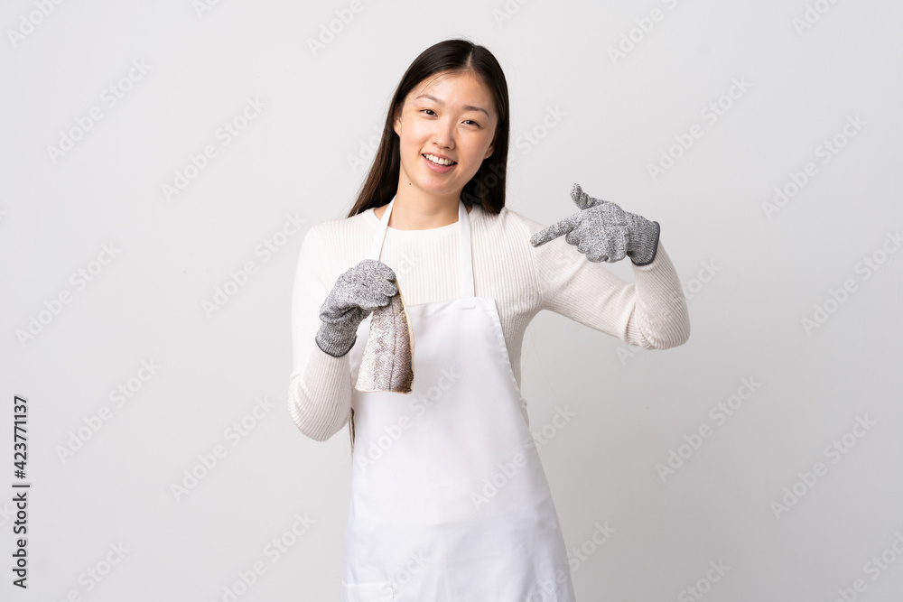 Chinese fishmonger wearing an apron and holding a raw fish over isolated white background proud and self-satisfied Chinese fishmonger wearing an apron and holding a raw fish over isolated white background proud and self-satisfied