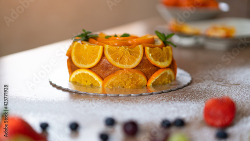 Homemade orange cake with sliced oranges in a kitchen