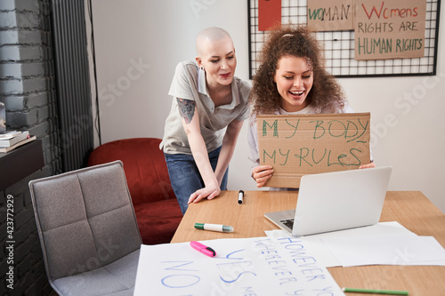 Girls showing cupboard poster to the laptop screen while consulting online