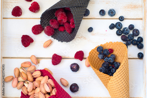 Fresh assortment of delicious vegan snacks - pistachio nuts, raspberries and blueberries in cruchy ice cream cornet photo