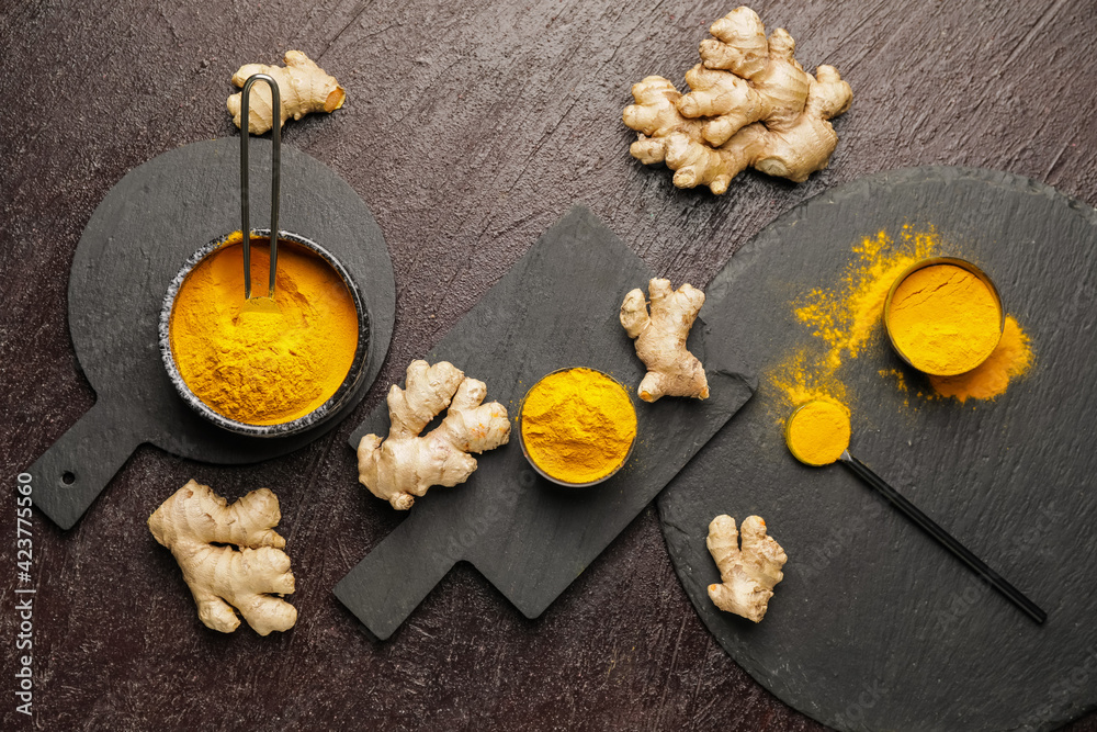 Composition with turmeric powder and roots on dark background Composition with turmeric powder and roots on dark background