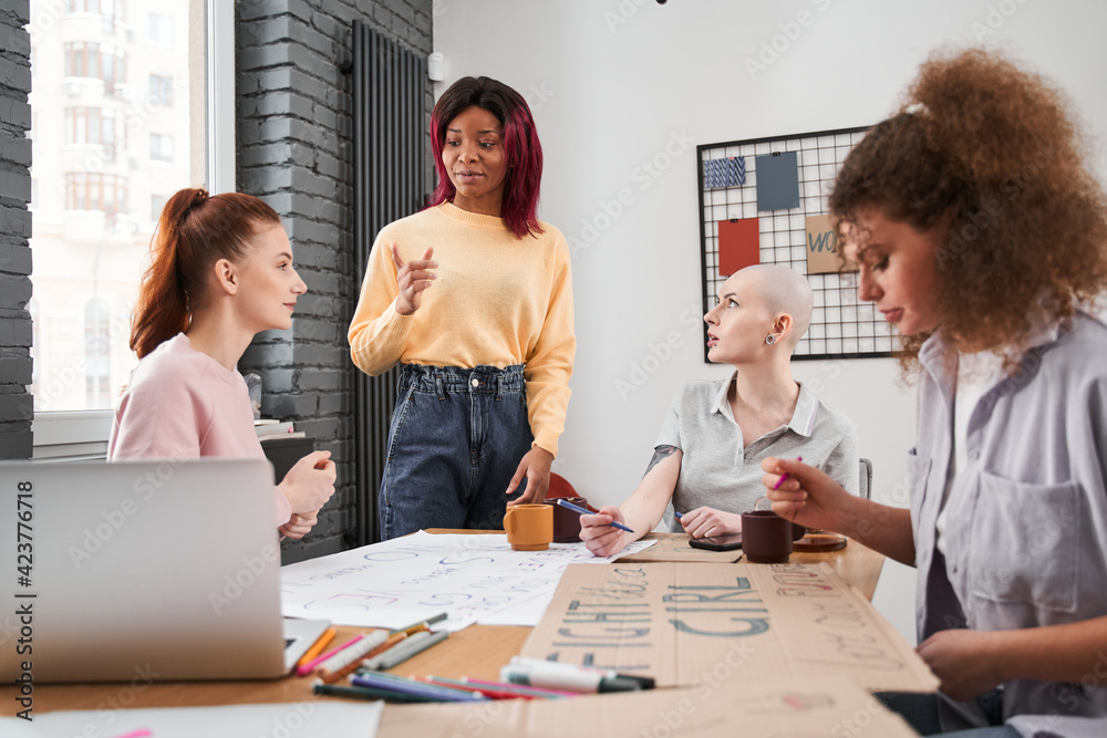 Obraz premium Girl telling something about feminism to her girlfriends at the office