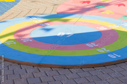 wooden multi-colored target lies on the sidewalk