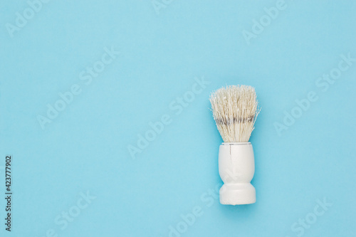 Stylish white shaving brush on a light blue background.