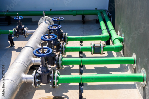 Piping systems on the roof of a large high-rise building. Pump systems and doors that open and close are commonly installed on pipes in the chemical industry, power plants, oil and gas.