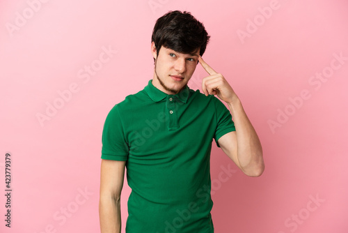 Young Russian man isolated on pink background making the gesture of madness putting finger on the head © luismolinero