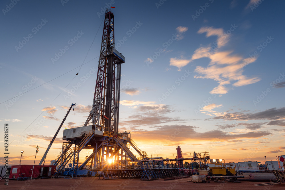 Sunrise at drilling rig in oil field, onshore petroleum industry