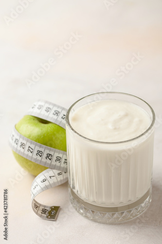 Glass of yogurt, apple and measuring tape on the table. Diet nutrition
