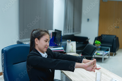 Asian officer woman stretching body at the desk of office from back angle,Thailand people,Businesswoman tired from hard work © reewungjunerr