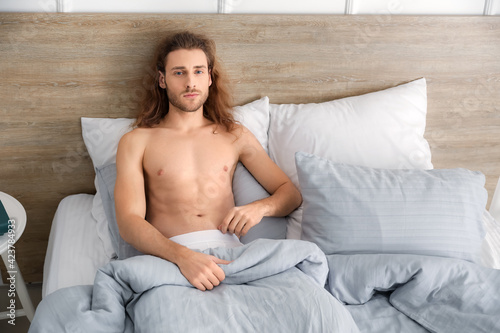Sexy young man sitting in b...