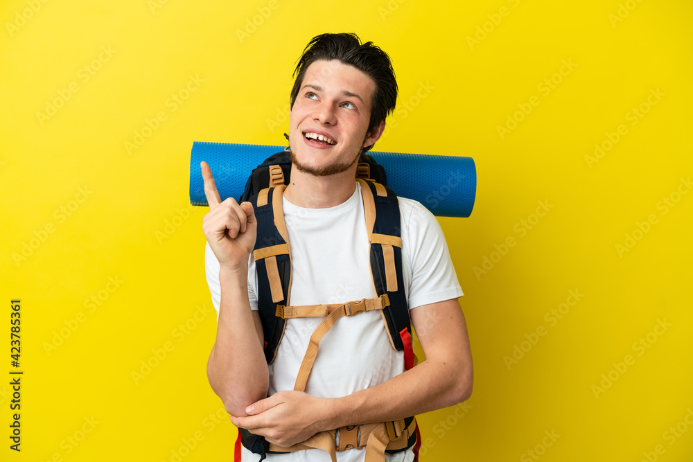 Young mountaineer Russian man with a big backpack isolated on yellow background pointing up a great idea Young mountaineer Russian man with a big backpack isolated on yellow background pointing up a great idea