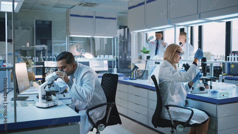 Team of Medical Research Scientists Conduct Experiments with Help of Microscope, Test Tubes, Micropipette and Writing Down Analysis Results on a Computer. Modern Biological Applied Science Laboratory. Team of Medical Research Scientists Conduct Experiments with Help of Microscope, Test Tubes, Micropipette and Writing Down Analysis Results on a Computer. Modern Biological Applied Science Laboratory.