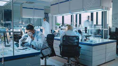 Team of Medical Research Scientists Conduct Experiments with Help of Microscope, Test Tubes, Micropipette and Writing Down Analysis Results on a Computer. Science Laboratory with Blurred Motion.