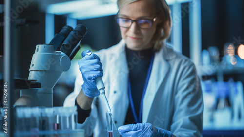 Female Research Scientist Uses Micropipette to Extract a Sample on a Microscope Slide to Analyse it Under the Scope in a Modern Laboratory. Scientists Working with Help of Technology and Computers. photo