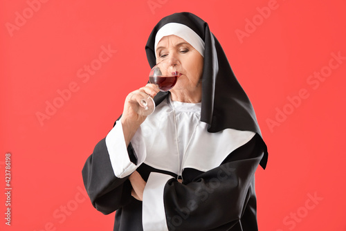 Senior nun with alcohol on color background