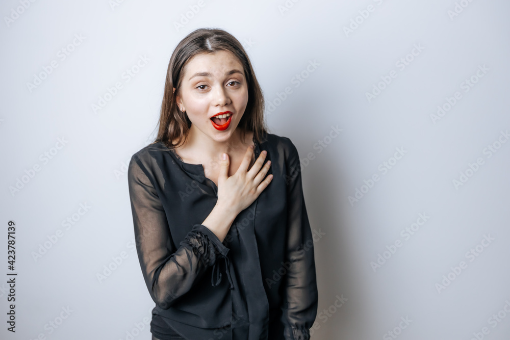 The woman with the red lips opened her mouth in surprise against the light gray background The woman with the red lips opened her mouth in surprise against the light gray background