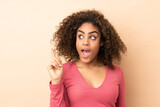 Young African American woman isolated on beige background intending to realizes the solution while lifting a finger up