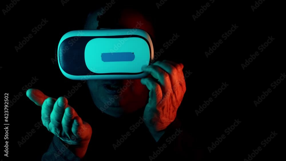 middle-aged man in a dark room with neon lights in modern VR glasses interacting with network while having virtual reality experience, concept study of parallel reality, another world middle-aged man in a dark room with neon lights in modern VR glasses interacting with network while having virtual reality experience, concept study of parallel reality, another world