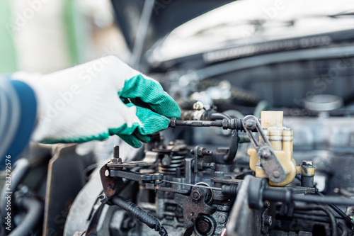 auto mechanic regulates fuel supply with throttle cable lever, idle setting.