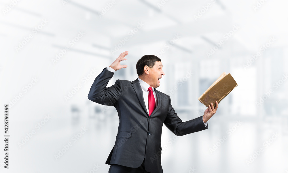 Expressive businessman looking in open book Expressive businessman looking in open book