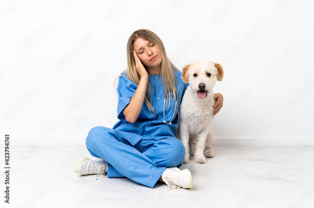 Young veterinarian woman with dog sitting on the floor with headache