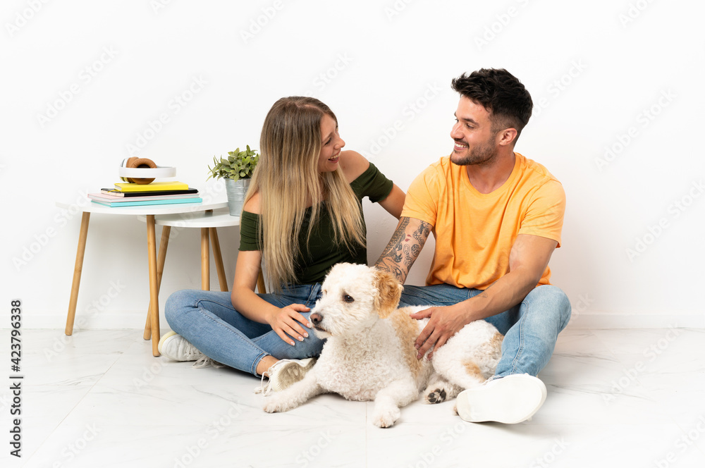 Young caucasian couple with dog staying at home happy and smiling