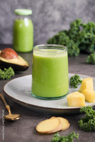 A glass of natural kale smoothie with variety fruit and herb such as pineapple, avocado, ginger. Green smoothies are nutrient-rich blends of fruits and green vegetables with a lot of health benefits 