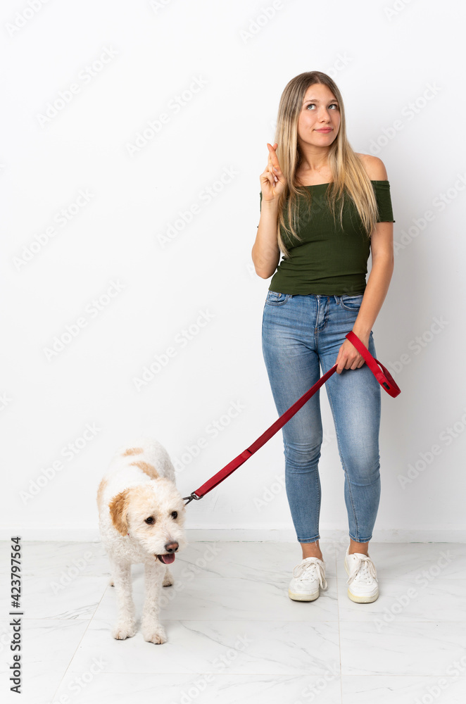 Young caucasian woman walking the dog isolated on white background with fingers crossing and wishing the best Young caucasian woman walking the dog isolated on white background with fingers crossing and wishing the best