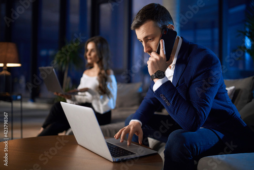 Man and woman working on laptops at home